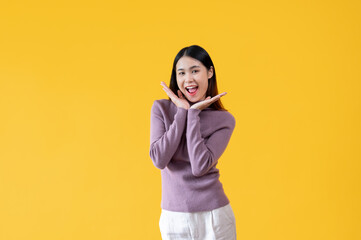 A cute Asian woman stands against an isolated yellow background with a cute face and posture.