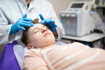 a cosmetologist doctor makes cosmetic procedures on the face of a young guy in a beauty salon