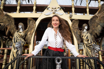 a beautiful girl in a pirate costume on the deck of a ship.