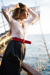 a beautiful girl in a pirate costume on the deck of a ship.