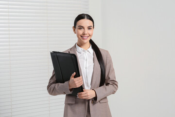 Beautiful real estate agent with documents indoors