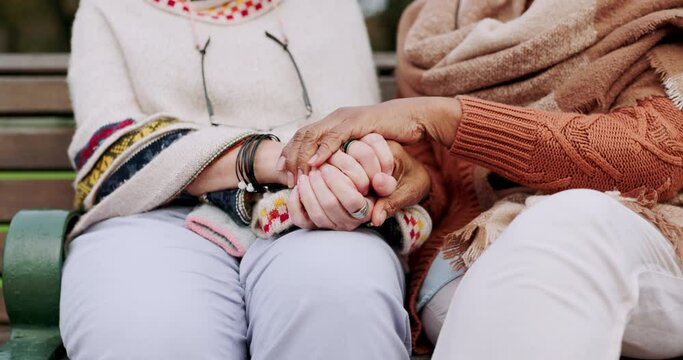 Senior friends, care and holding hands with support, comfort and hope outdoor. Bench, park sitting and mature people with retirement, empathy and kindness gesture for friendship and trust together