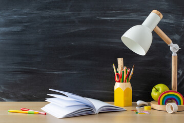 Enhance productivity with this student's study setup. Side view image featuring lamp and stationery on wooden table on chalkboard isolated background, providing ample space for text or advertising