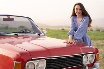beautiful girl in retro style posing near vintage red cabriolet car.