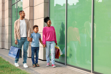 Family shopping. Happy parents and son with colorful bags near mall outdoors