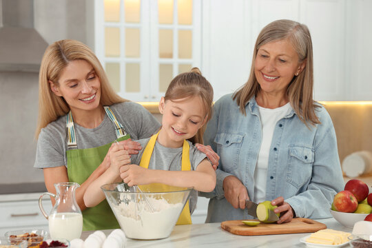 Three generations. Happy grandmother, her daughter and granddaughter cooking together in kitchen