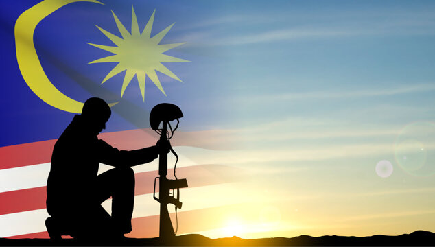 Silhouette of a soldier kneeling down with flag of Malaysia against the sunset. EPS10 vector