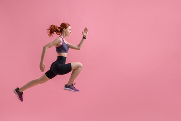 Fototapeta na wymiar Young woman in sportswear jumping on pink background, space for text