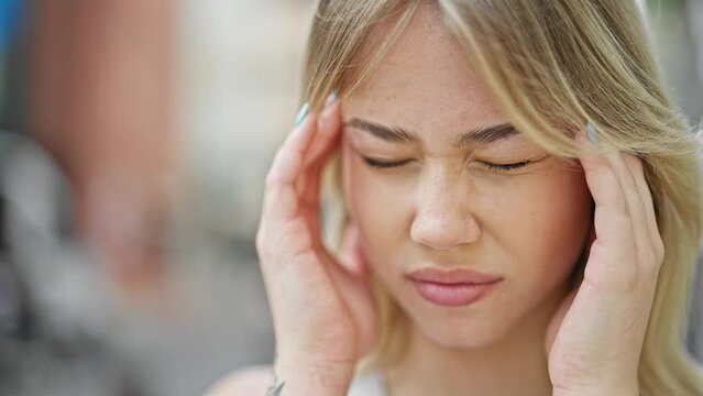 Young blonde woman suffering for headache at street
