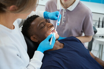 Female stomatologist looking at mouth mirror checking teeth