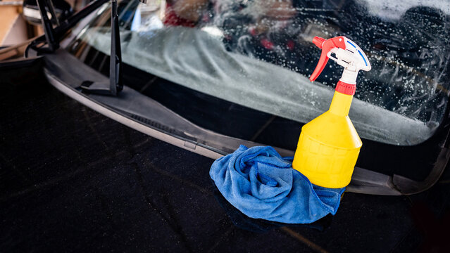Yellow foggy spray bottle of soapy solution with blue rag or cloth wipe. Cleaning tool for car wash and car window film tint installation