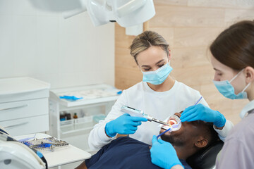 High-qualified woman dentist using contemporary oral anesthesia injector