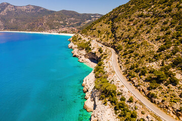 Aerial view of a road running between mountain and sea, road trip at summer vacation