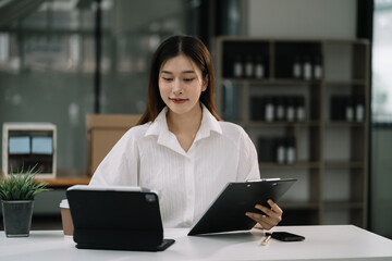 Business women hand working with tablet and laptop computer with documents on office desk in modern office.