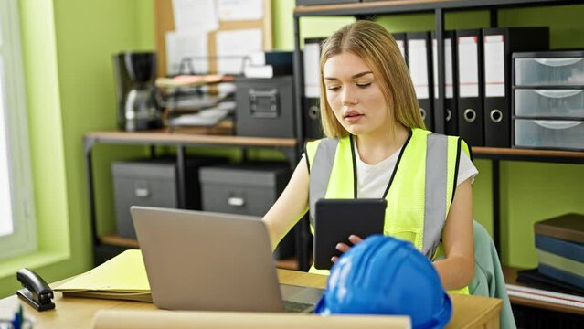 Young blonde woman architect using laptop and touchpad at office
