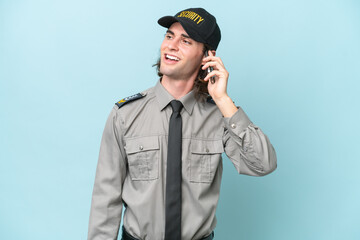 Young safeguard man isolated on blue background keeping a conversation with the mobile phone with...