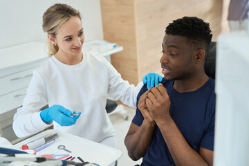 Obraz premium Woman dental technician showing medical tools to young scared man