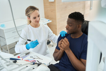 Dentist taking dental drill and assuring patient that it will not hurt