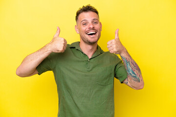 Young caucasian handsome man isolated on yellow background giving a thumbs up gesture