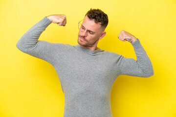 Young caucasian handsome man isolated on yellow background doing strong gesture