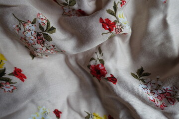 Soft folds on light beige cotton fabric with colorful floral print