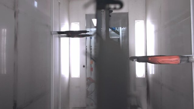 Slow motion panning shot of an industrial painting robot, painting a metal sheet