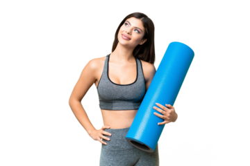 Young sport woman going to yoga classes while holding a mat over isolated chroma key background posing with arms at hip and smiling