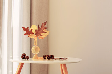 autumn leaves in glass vase in modern interior