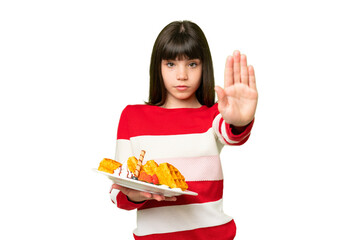 Little girl holding waffles over isolated chroma key background making stop gesture