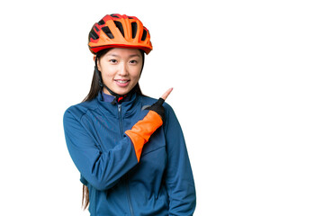 Young cyclist woman over isolated chroma key background pointing to the side to present a product