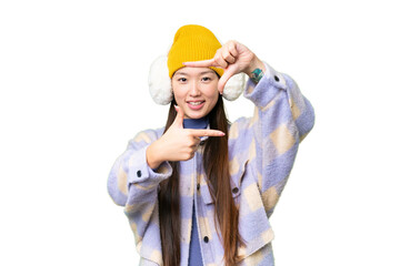 Young Asian woman wearing winter muffs over isolated chroma key background focusing face. Framing symbol