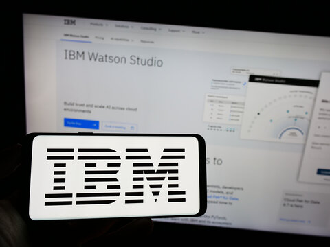 Stuttgart, Germany - 07-29-2023: Person holding mobile phone with logo of International Business Machines Corporation (IBM) on screen in front of web page. Focus on phone display.