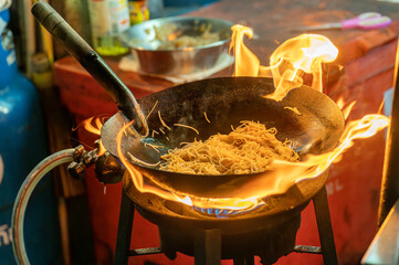 fried noodles cook in pan with big fire flame is hong kong style. Pad Thai favorite and famous...