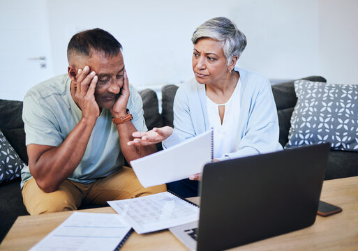 Frustrated senior couple, documents and laptop in debt, financial crisis or struggle on sofa at home. Upset elderly man and woman in disagreement, argument or fight with finance, bills or expenses