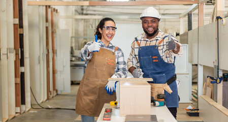 Two confident young carpenter teamwork coworker colleague standing look at camera and smile in workshop. man and women worker carpenter entrepreneur stand working in workbench shop carpentry