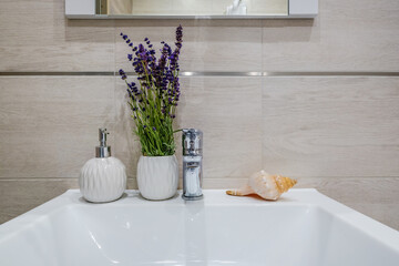 metal water tap with sink and faucet with bouquet of lavender flowers and shell in expensive bathroom