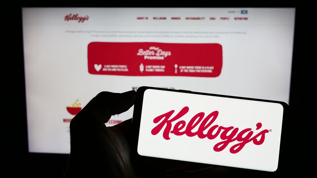 Stuttgart, Germany - 07-29-2023: Person holding smartphone with logo of US business The Kellogg Company (Kellogg's) on screen in front of website. Focus on phone display.