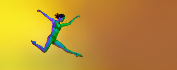 Dynamic image of young artistic, expressive woman dancing in underwear against gradient yellow orange background in neon. Concept of modern dance style, hobby, art, performance, lifestyle, ad. Banner