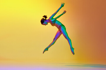 Fototapeta na wymiar Talented, flexible young woman dancing contemp in underwear against gradient yellow orange background in neon light. Concept of modern dance style, hobby, art, performance, lifestyle, ad