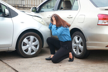 Stressed Asian woman holding her head sitting on the road Look at the cars that were hit. Transportation concept. car accident insurance