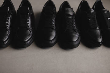 Three pairs of black sneakers on the floor. Casual fashion style minimalistic shoes.