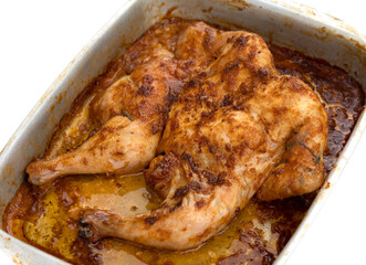 Baked chicken on a baking sheet. Chicken baked in the oven on a baking sheet close-up isolated on a white background.