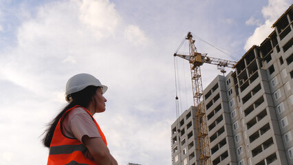 Female civil engineer, architect during work. The construction crane is moving at a height.