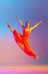 Elegant, graceful young woman dancing in red dress against gradient multicolored background in neon light. Concept of modern dance style, hobby, art, performance, lifestyle, ad