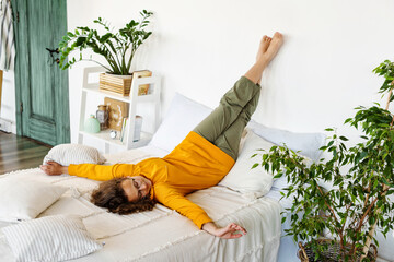Teen girl is lying on bed with legs up at home and nothing to do. Stress relief after study....