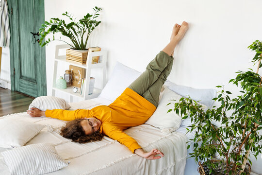 Teen girl is lying on bed with legs up at home and nothing to do. Stress relief after study. Relaxing, enjoy, pastime.