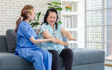 Obraz premium Asian young professional female doctor in blue hospital uniform sitting on sofa couch holding hand touching supporting taking care happy old chubby retirement patient in ward clinic living room