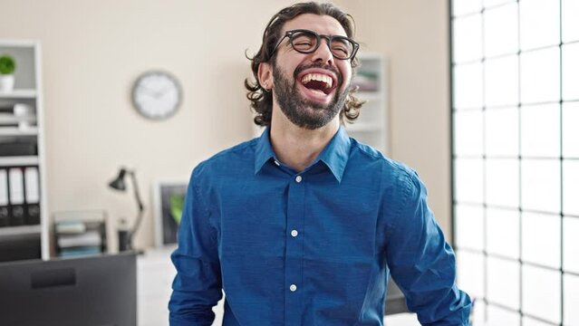 Young hispanic man business worker laughing a lot at the office