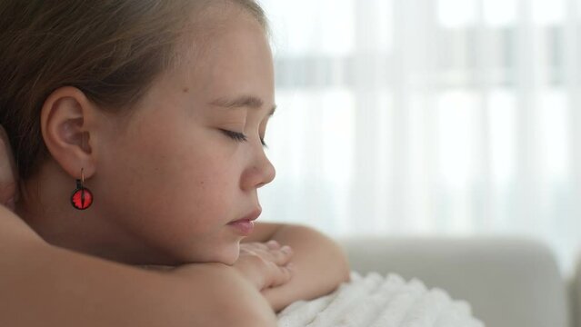 Closeup side view of pretty relaxed girl having neck, shoulder and back massage by unrecognizable female masseuse lying on massage table. Adorable kid getting physiotherapy from masseuse for body care