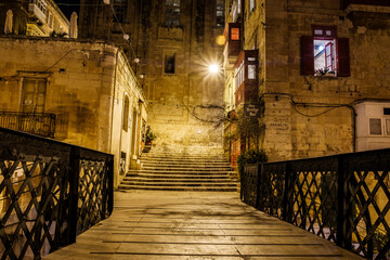 the empty streets of Valletta at night. Street lights illuminate the old houses